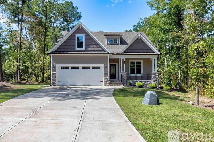 A house with a garage is surrounded by trees.