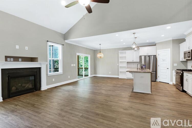 A spacious living room with a fireplace and a kitchen area in the background.