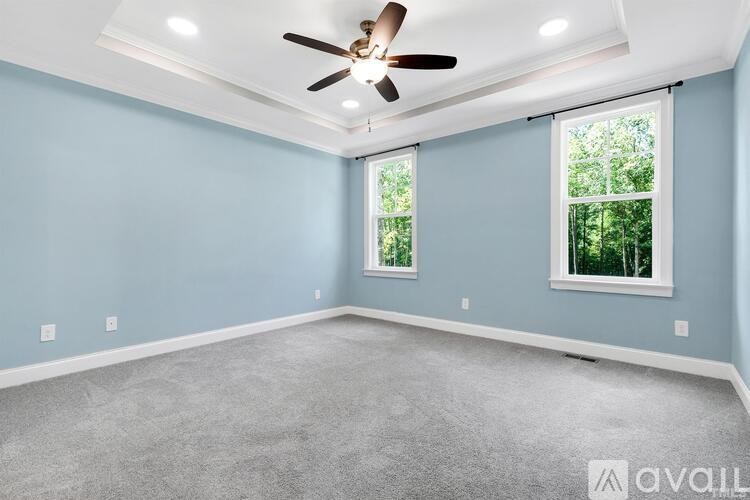 A room with a ceiling fan and two windows.