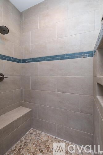 A shower area with a bench and tiled floor.