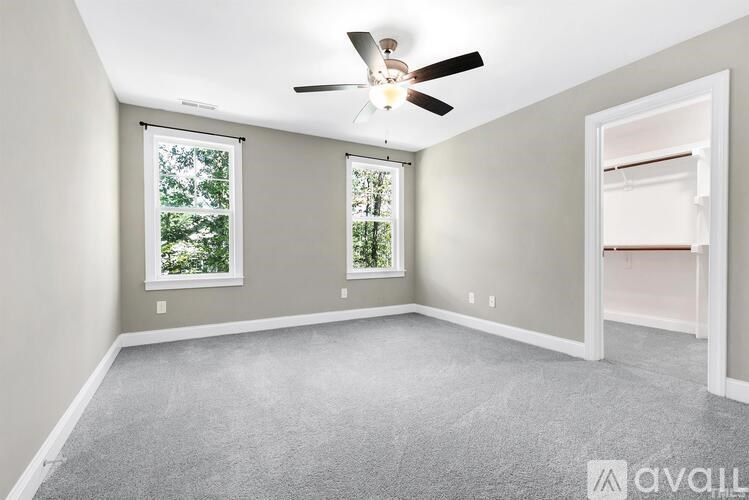 A room with a ceiling fan and two windows.