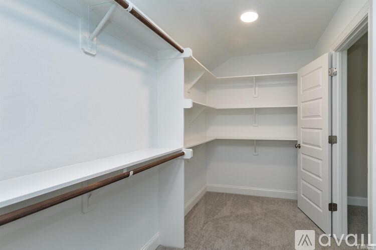 A white wall with a brown shelf and a door on the right.