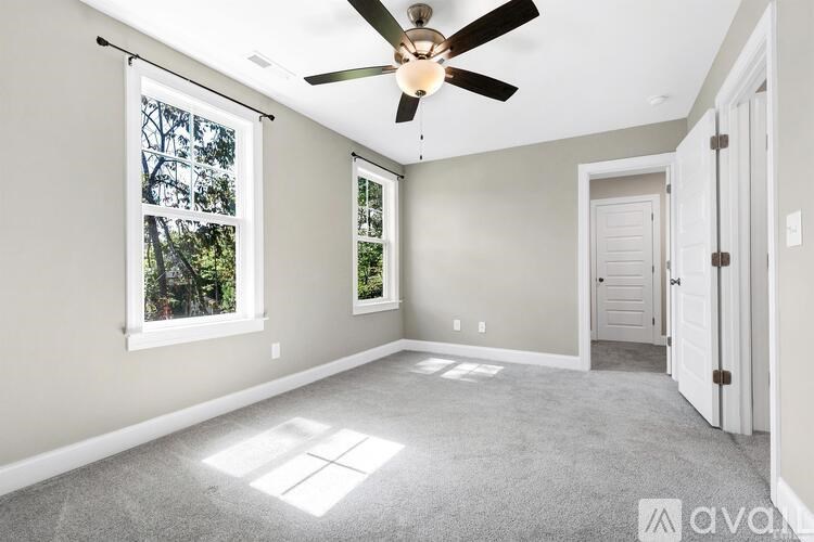 A room with a ceiling fan and a window letting in sunlight.