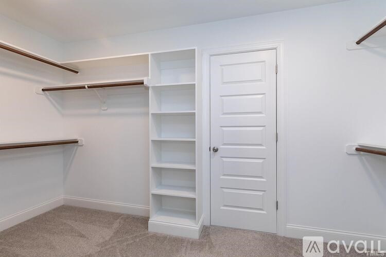 A white door is in a room with a carpeted floor and a wall with shelves.