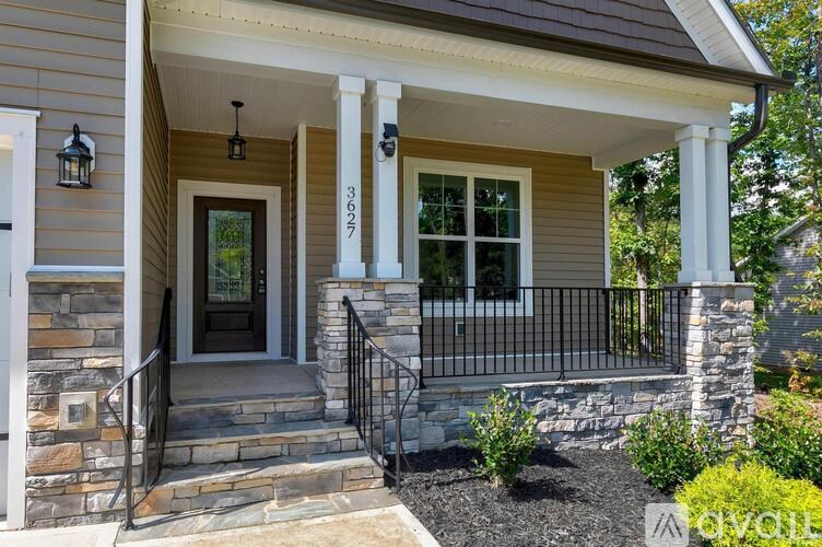 A house with a front porch and a black railing.