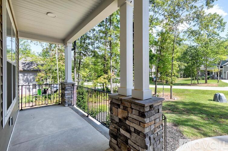 A porch with a white ceiling and a black railing.