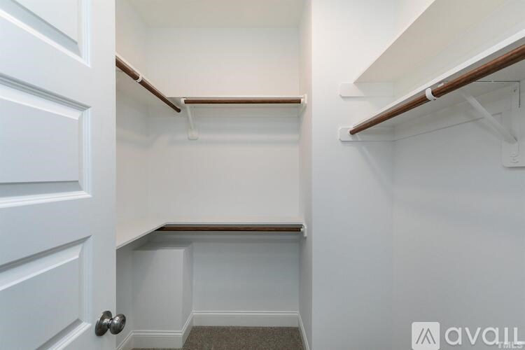 A white door opens to a small, empty room with a shelf and a carpeted floor.
