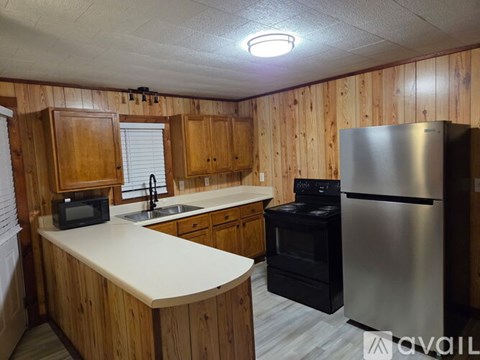 A kitchen with wooden cabinets and a stainless steel refrigerator.