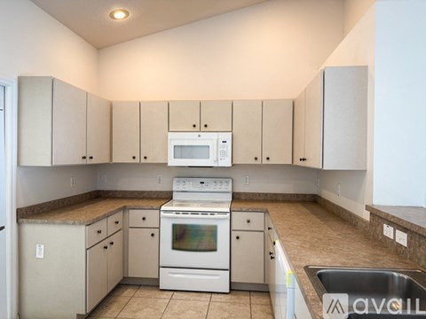A kitchen with white cabinets and a stove top oven.
