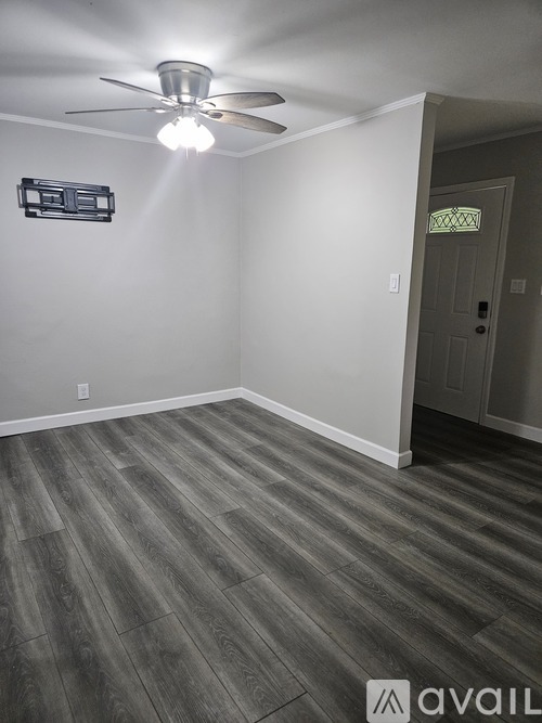 A room with a ceiling fan and wooden flooring.