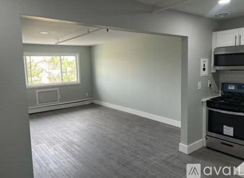 A spacious empty room with a window and a microwave.