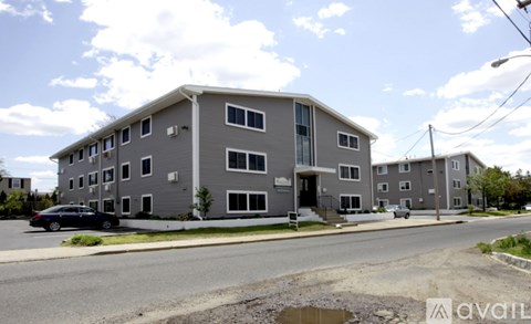A grey apartment building with a black car parked in front.