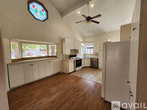 A kitchen with white cabinets and a ceiling fan.