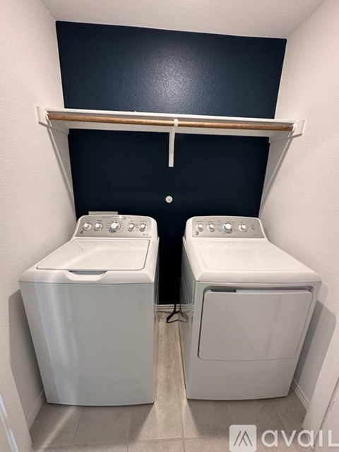 Two white front load washing machines in a small laundry room.