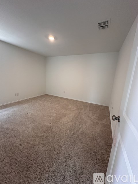 A room with a carpeted floor and a door on the right side.