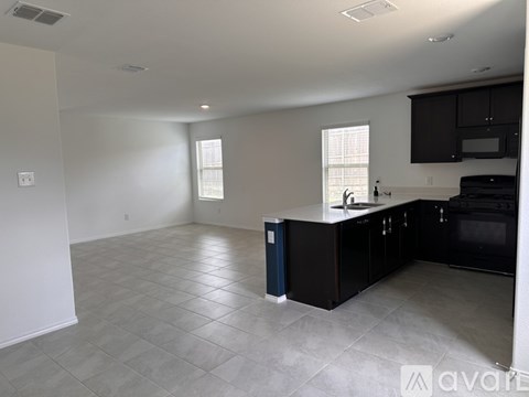 A kitchen with black cabinets and a blue trash can.
