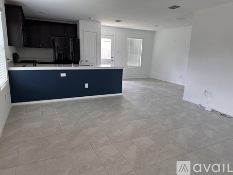 A kitchen with a dark blue island and light grey tiled floor.