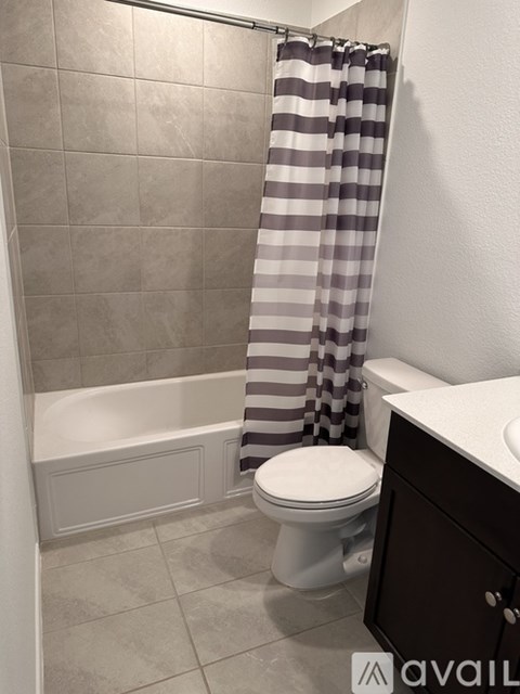 A bathroom with a toilet, a shower curtain, and a tiled shower wall.