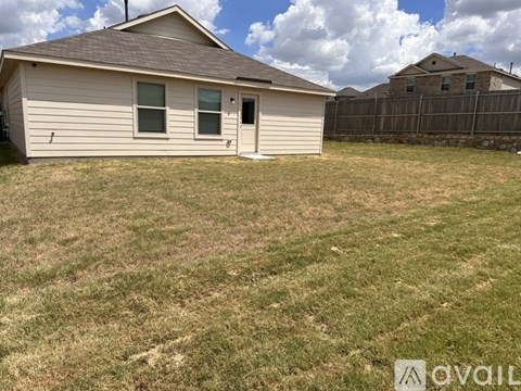 A small house with a brown roof and a white door is surrounded by a grassy area.