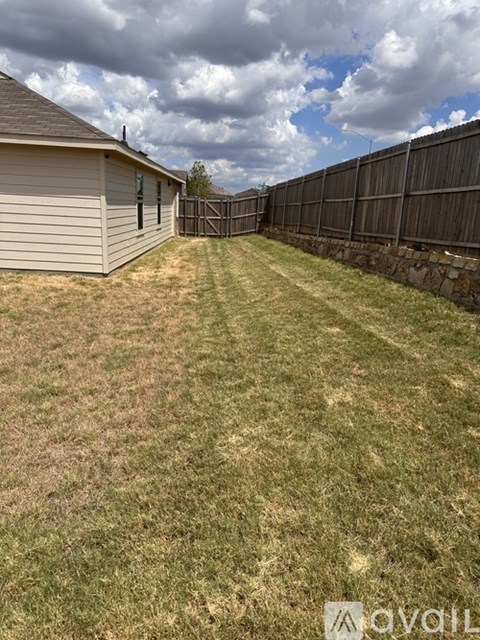 A backyard with a fence and a house.