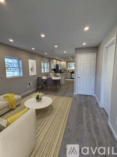 A living room with a white couch and a dining table with chairs.