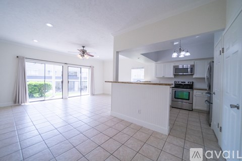 A spacious kitchen and living room with white tiled floors and a ceiling fan.