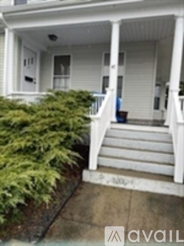 A white house with a porch and steps leading to the front door.