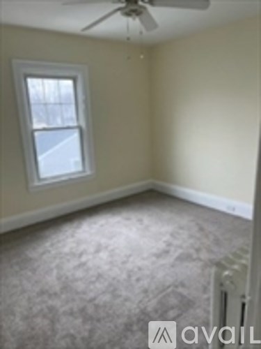 A room with a carpeted floor and a window.