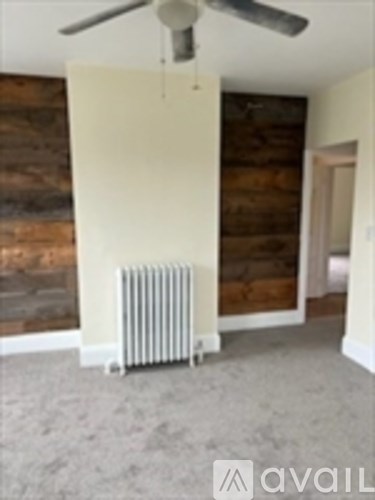 A room with a fan and a radiator on the floor.