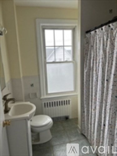 A bathroom with a toilet, sink, and window.