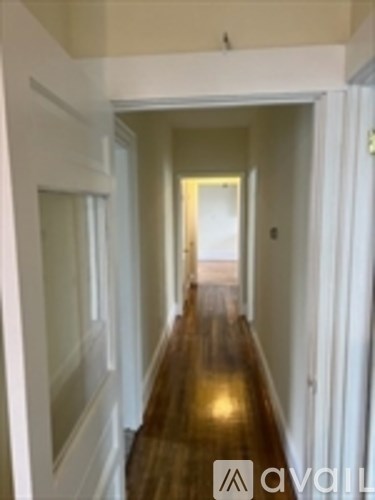 A hallway with a wooden floor and white walls.