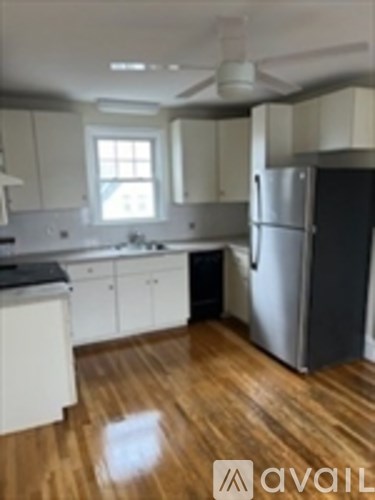 A kitchen with a refrigerator and wooden floors.