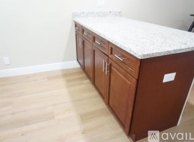 A kitchen island with a granite countertop and wooden cabinets.