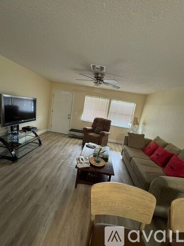 A living room with a television, a couch, a chair, and a coffee table.