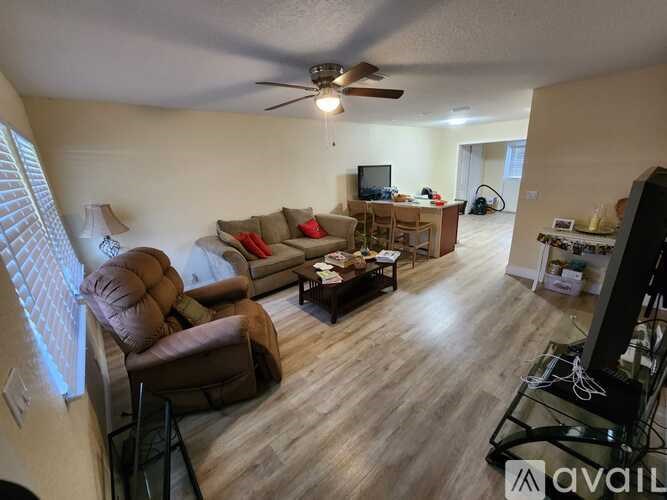 A living room with a brown couch and a ceiling fan.