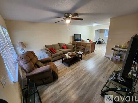 A living room with a brown couch and a ceiling fan.