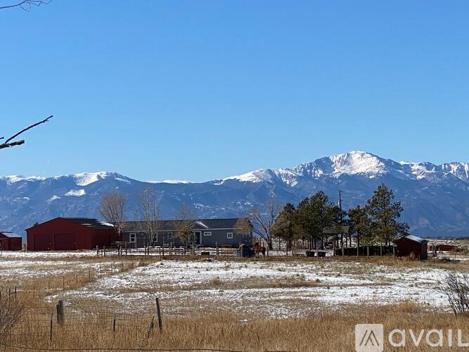 A farm with a red barn and a mountain in the background.