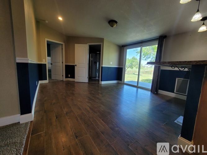 A spacious room with wooden flooring and a large window.
