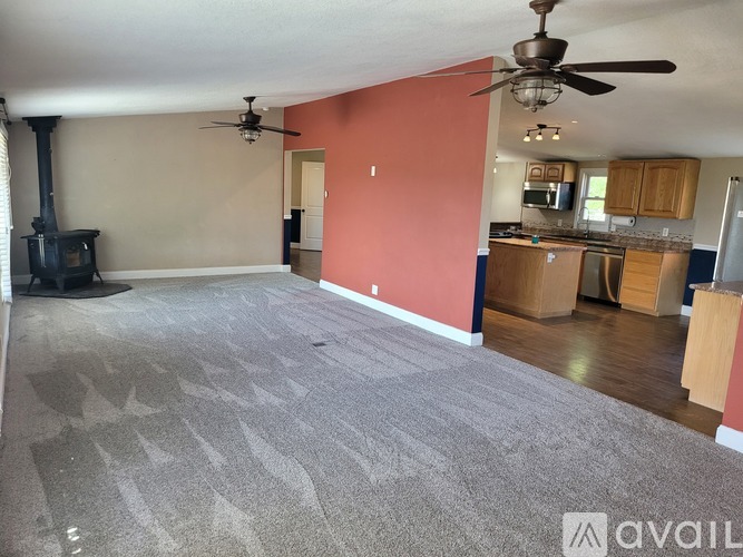 A living room with a fireplace and a grey carpet.