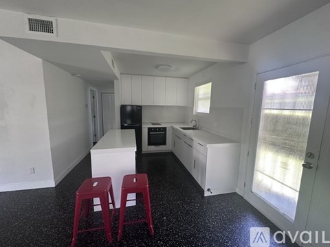 A kitchen with white cabinets and a black floor.