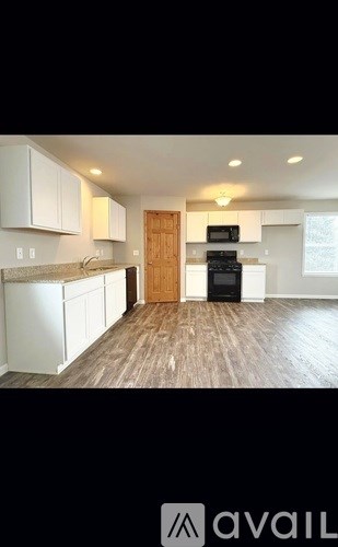 A kitchen with white cabinets and a wooden floor.