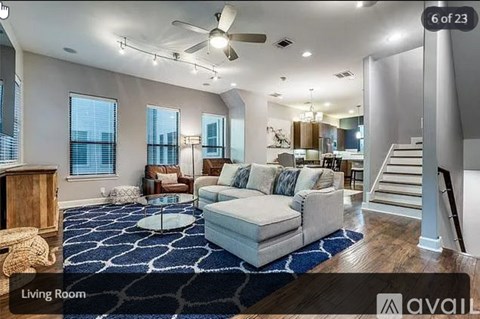 A living room with a white couch and a blue rug.