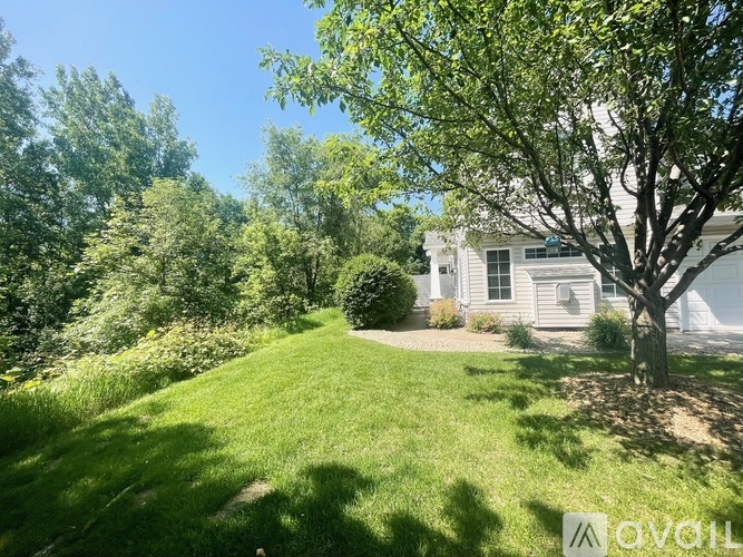 A tree stands in a yard in front of a house.