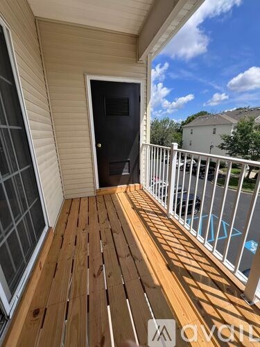 A wooden deck with a black door and a white railing.