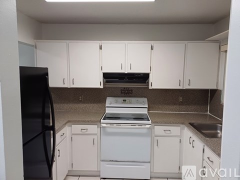 A kitchen with white cabinets and a black fridge.
