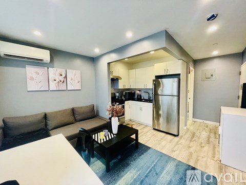 A modern living room with a grey sofa and a coffee table in front of a kitchen.
