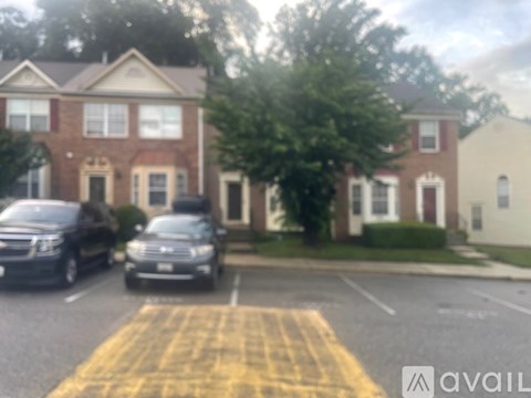 Two cars parked in a parking lot in front of a brick building.