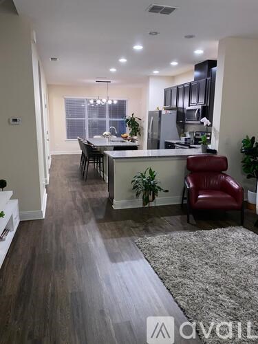 A living room with a kitchen in the background and a red chair in the foreground.