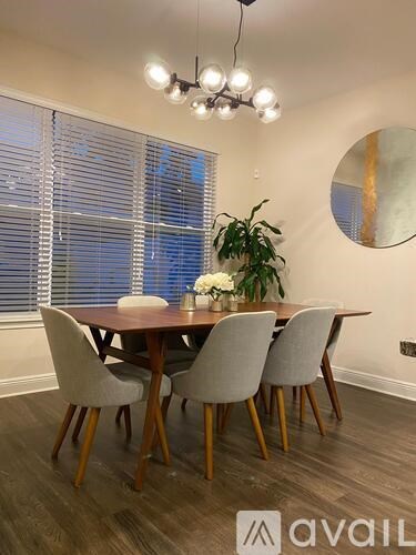 A dining room with a round mirror and a table with chairs.