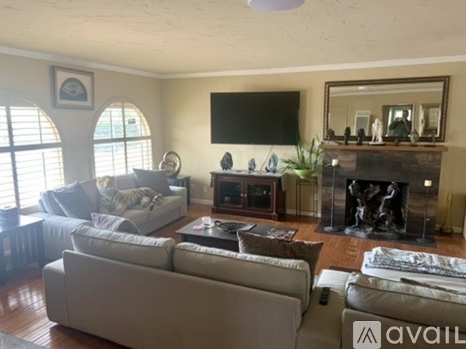 A living room with a fireplace and a flat screen TV mounted on the wall.